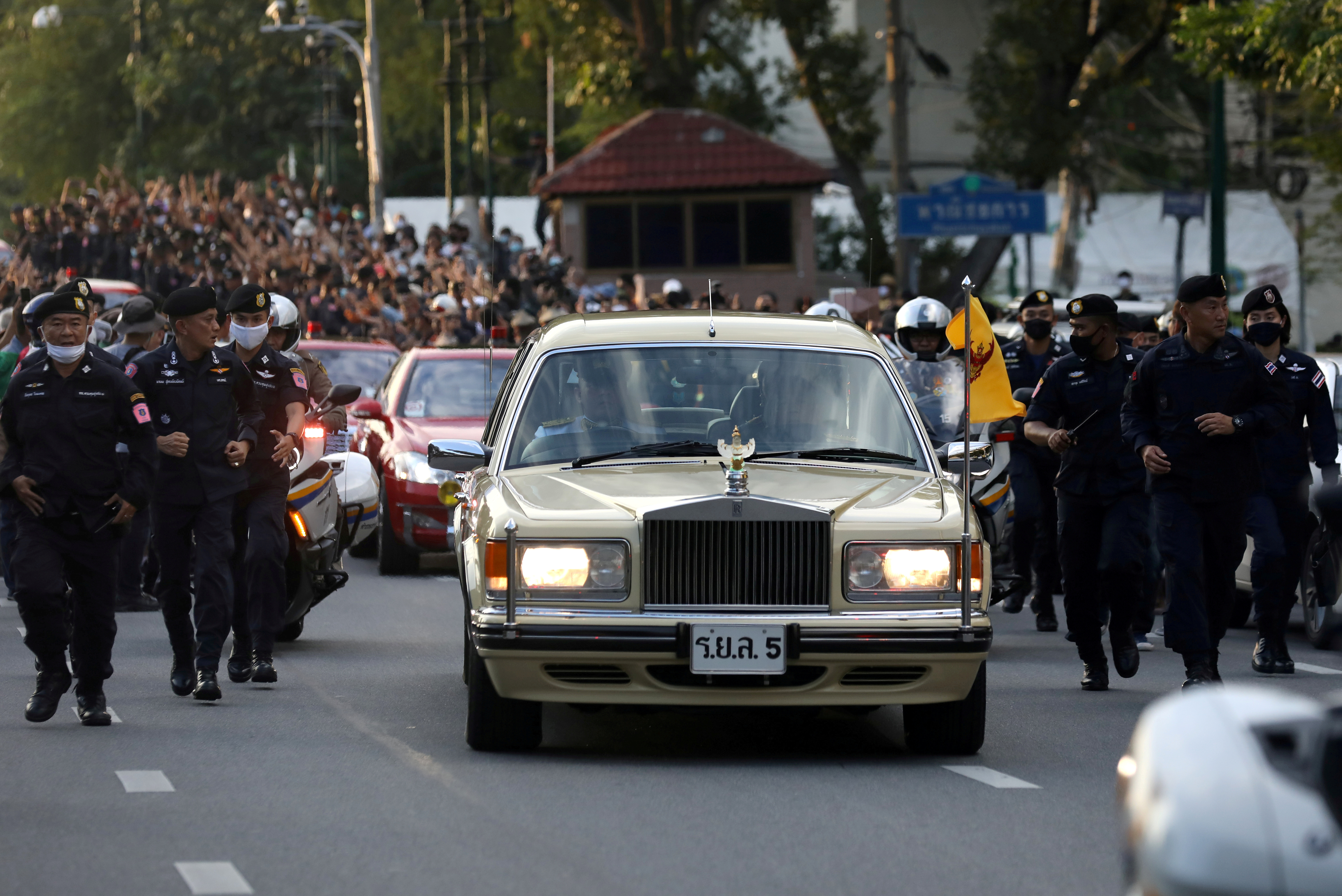 FILE PHOTO: The royal motorcade carrying Thailand's Queen Suthida and Prince Dipangkorn drives past a group of anti-government demonstrators in front of Government House in Bangkok