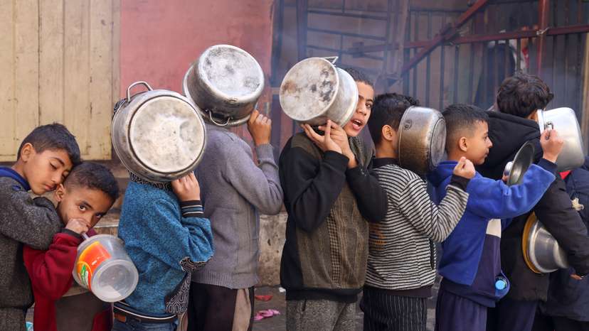 FILE PHOTO: Palestinian children carry pots as they queue to receive food cooked by a charity kitchen, in Rafah in the southern Gaza Strip
