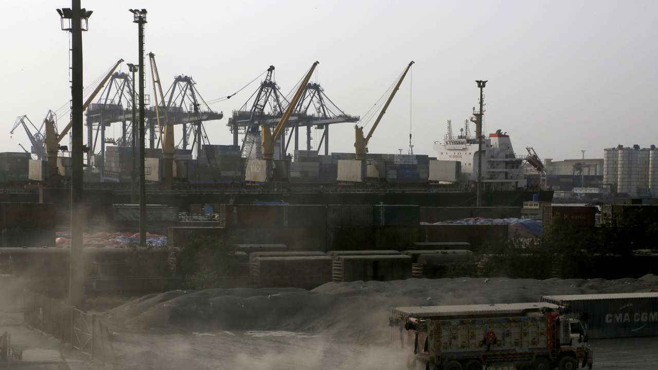 A truck moves past cranes during a media tour of the Karachi Port