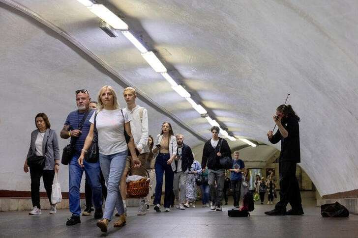 FILE PHOTO: A man plays the violin as people walk in a subway station during morning rush hour in central Kyiv