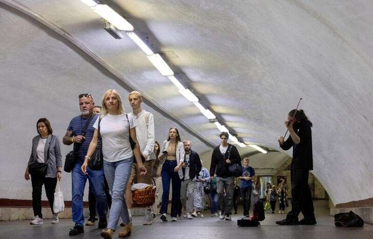 FILE PHOTO: A man plays the violin as people walk in a subway station during morning rush hour in central Kyiv